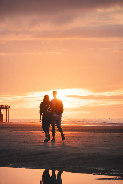 Paseo romántico de una joven pareja en las playas de Oostende en el oeste de Bélgica al atardecer. Amor y devoción. Reflejo en una piscina de agua. - Foto, imagen