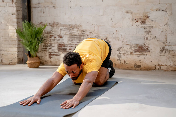Young man practicing yoga, stretching back sitting pose in a industrial gym. High quality photo - Φωτογραφία, εικόνα