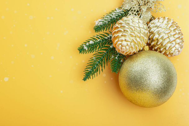 Традиционная новогодняя композиция. Праздничный декор, снежные ветки елки, шары, золотые цветы. Цветной абрикосовый фон, плоский узор, вид сверху - Фото, изображение