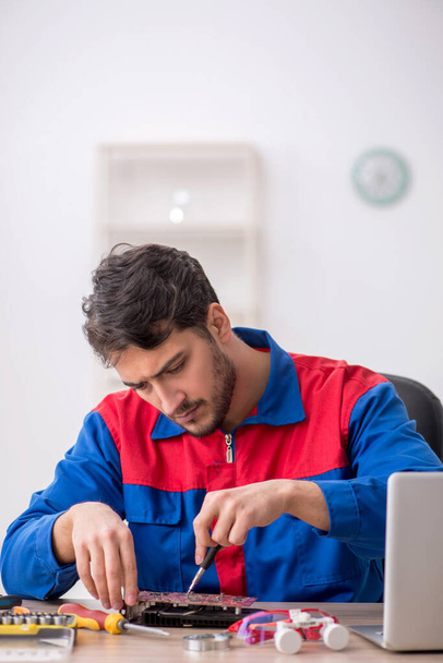 Jonge reparateur repareert computer in het lab - Foto, afbeelding