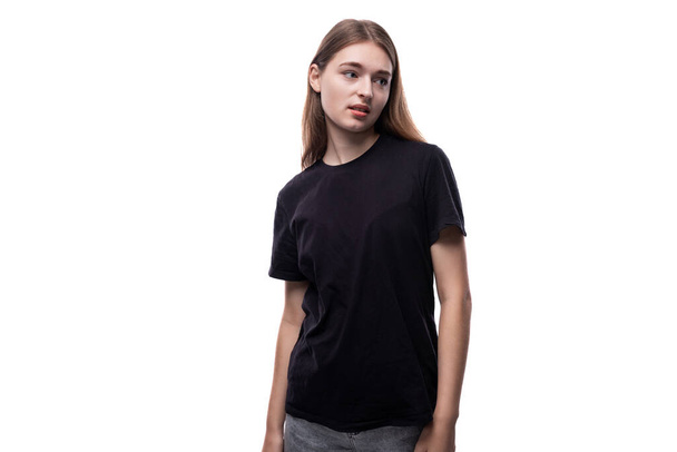 Een schoolmeisje met blond haar in een zwart T-shirt met een modeluitstraling. - Foto, afbeelding