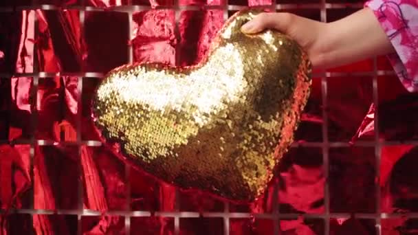 Γυναίκα φορώντας ροζ υφάσματα με καρδιές και κρατώντας χρυσή καρδιά μαξιλάρι - Πλάνα, βίντεο