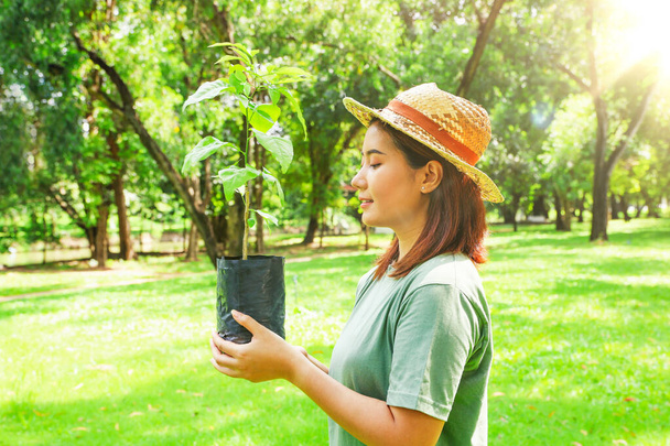 Joyeux volontaire jeune femme asiatique tenant de petits gaules se préparant à planter des arbres dans la forêt de jardin pour réduire le réchauffement climatique lors de la Journée mondiale de plantation d'arbres Fille bénévole faisant un bon service à la société. - Photo, image