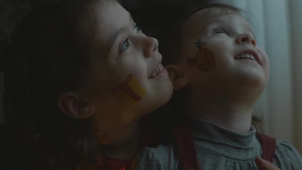 Vrolijke kleine meisjes met kerst thema schilderijen op hun gezicht. Samen spelen op het feest. Kerstconcept - Video