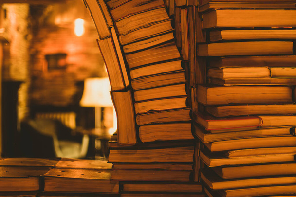 鏡に映る暖かい黄色いラプライトの本の山. 読書室のインテリアの背景 - 写真・画像