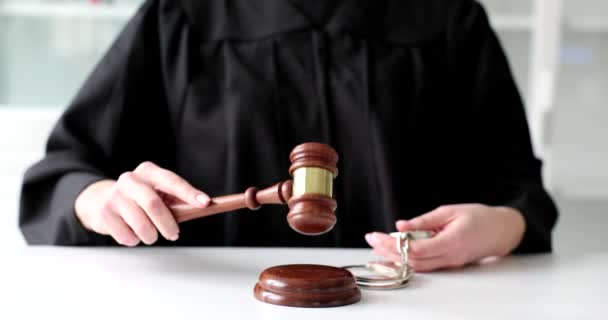 Sędzia trzyma kajdanki i puka młotkiem w ogrodzie sądu. Odpowiedzialność karna i orzeczenie sądu - Materiał filmowy, wideo