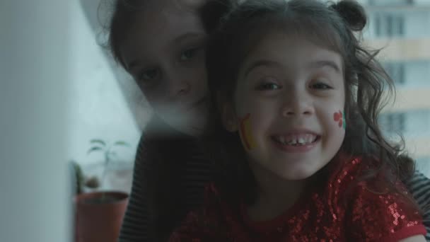 Iloisia pikkutyttöjä, joilla on jouluaiheisia maalauksia kasvoillaan. Katselen kameraa. Joulun käsite - Materiaali, video