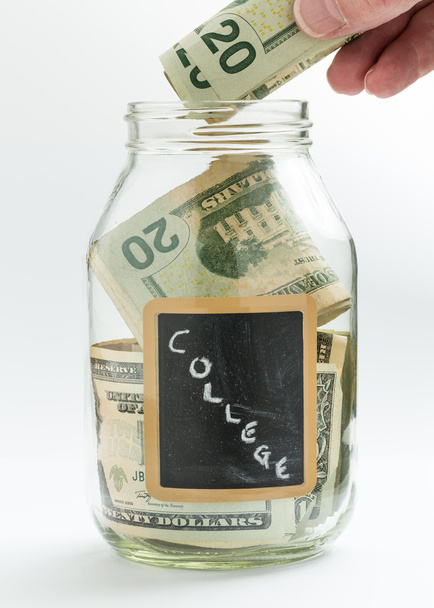 Hand inserting money into saving jar or bank - Photo, Image