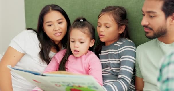 Mother, father and children reading a book on a bed in a family home for learning, quality time and bonding. A man, woman and girl kids in a bedroom together for a story and development with love. - Footage, Video