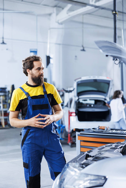 Engineer in repair shop using augmented reality holograms to check car specifications during checkup. Meticulous garage employee using futuristic AR technology to examine defective vehicle - Photo, Image