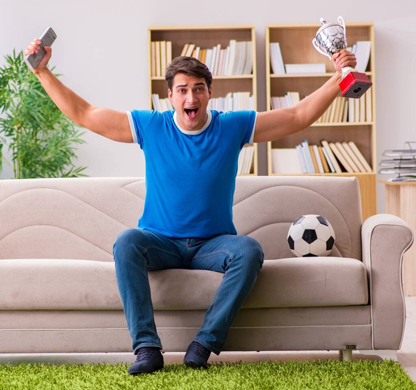 A férfi, aki otthon focit néz, a kanapén ül. - Fotó, kép