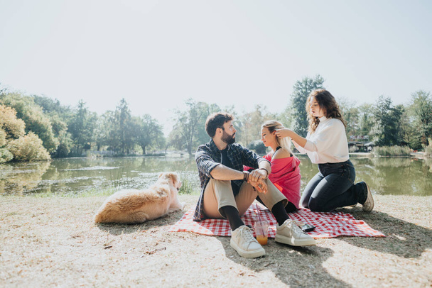 Amigos despreocupados disfrutan de un día soleado en un parque de la ciudad, descansando en la naturaleza, divirtiéndose chats y jugando con perros. La imagen perfecta de ocio alegre y energía positiva. - Foto, imagen