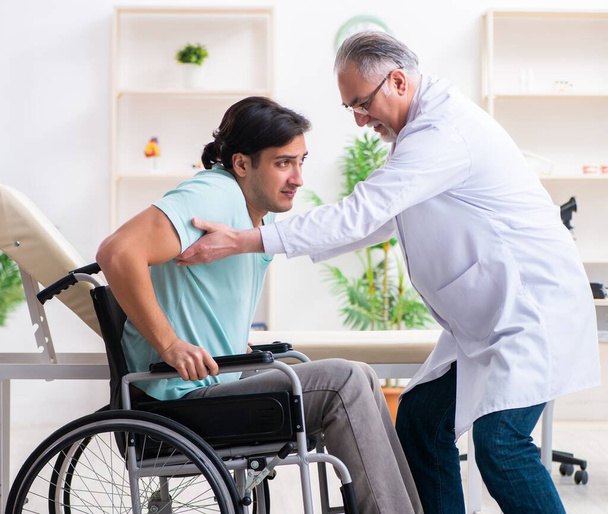 Le patient masculin en fauteuil roulant visitant un vieux médecin - Photo, image