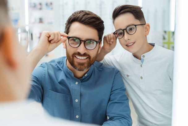 Smiling father and son wearing eyeglasses, posing in optics. Health care concept - Photo, Image