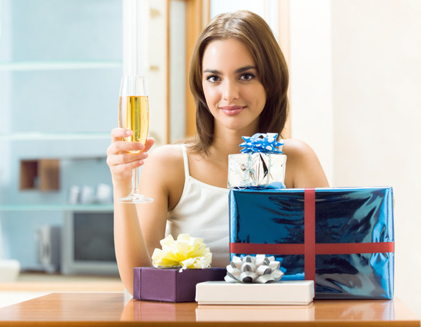 Woman with champagne and gifts at home - Foto, Imagen