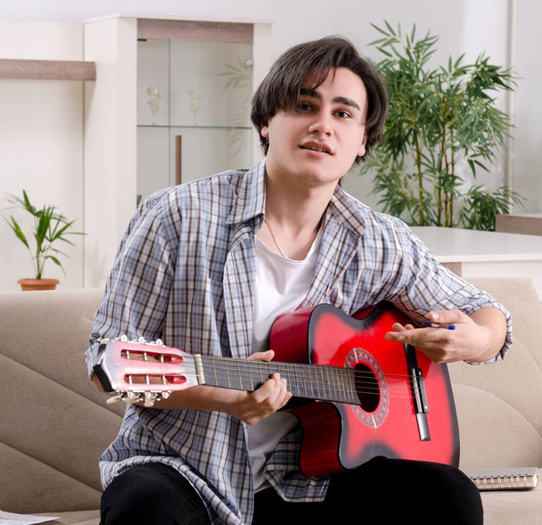 Il giovane con la chitarra a casa - Foto, immagini