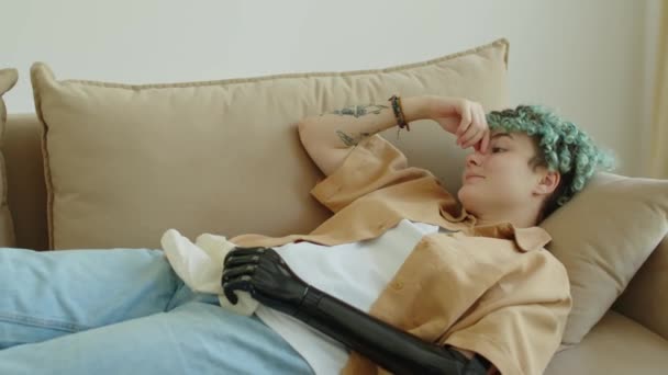 Triste ragazza Z con braccio protesico e capelli blu sdraiata sul divano, che tiene il tovagliolo e parla di emozioni durante la sessione di terapia - Filmati, video