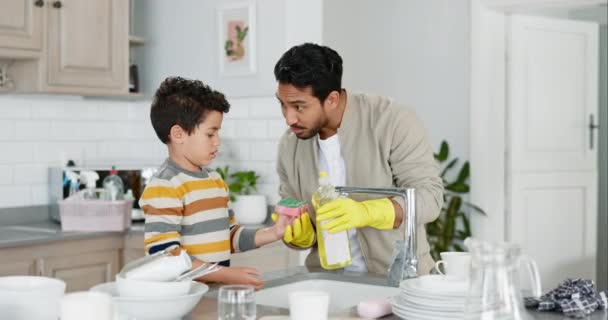 Ο μπαμπάς πλένει πιάτα, διδάσκει το παιδί και τον καθαρισμό με σαπούνι, νερό και σφουγγάρι στην κουζίνα, το σπίτι της οικογένειας και το αγόρι μαθαίνουν να καθαρίζουν γυαλί. Πατέρας, γιος βοηθούν και μαζί δουλεύουν στις δουλειές του σπιτιού.. - Πλάνα, βίντεο