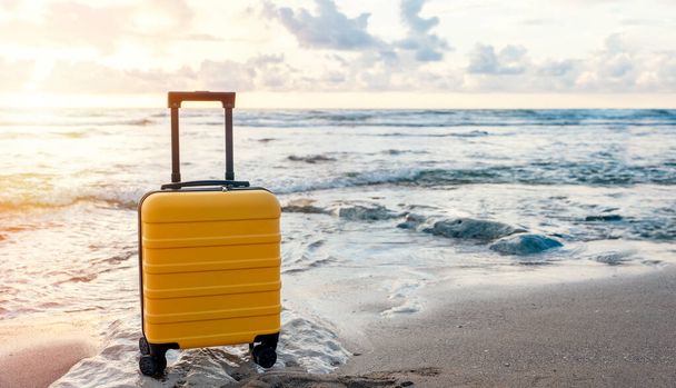 Sárga bőrönd a tengerparton a tenger ellen fantasztikus időben. Utasbiztosítás. Kevés az út. Utazási koncepció. - Fotó, kép