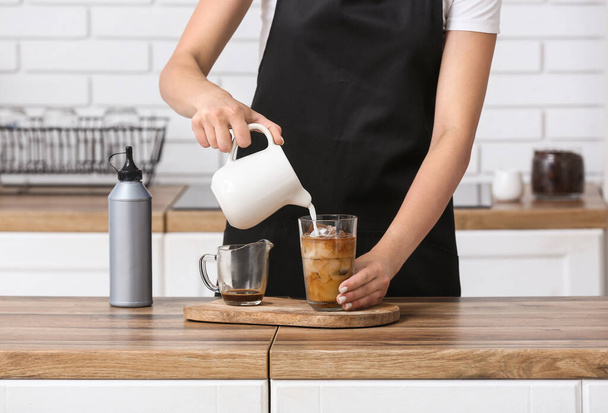 Female barista preparing tasty coffee on wooden table in kitchen - Photo, Image