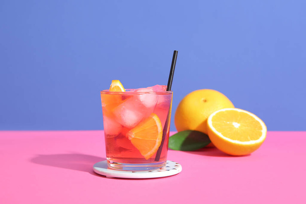 Glas leckerer Negroni-Cocktail und Orangen auf farbigem Hintergrund - Foto, Bild