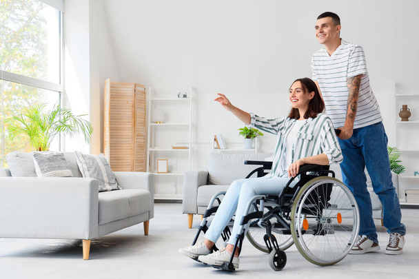 Молодий чоловік і його дружина в інвалідному візку вдома - Фото, зображення