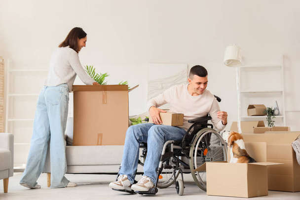 Young man in wheelchair and his wife with Beagle dog on moving day - Photo, Image