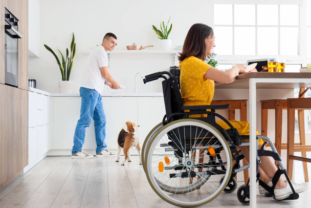 Mladý muž s bíglským psem a jeho ženou na invalidním vozíku doma - Fotografie, Obrázek