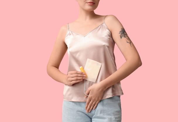 Schöne junge Frau mit Tampon und Menstruationskissen auf rosa Hintergrund, Nahaufnahme - Foto, Bild
