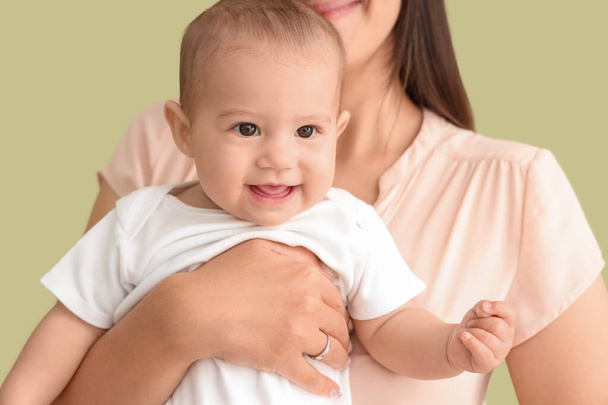 gelukkig moeder met haar kleine baby op groene achtergrond, close up - Foto, afbeelding
