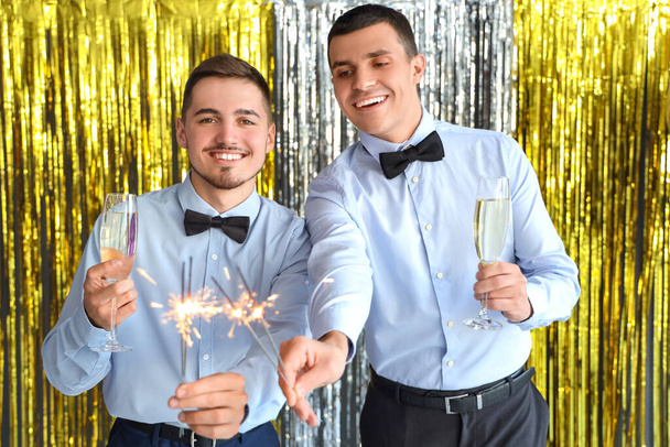 Männliche Freunde mit Champagner und Wunderkerzen bei Neujahrsparty - Foto, Bild