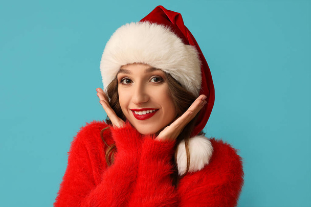 gelukkig jong vrouw in kerstman hoed op blauw achtergrond - Foto, afbeelding