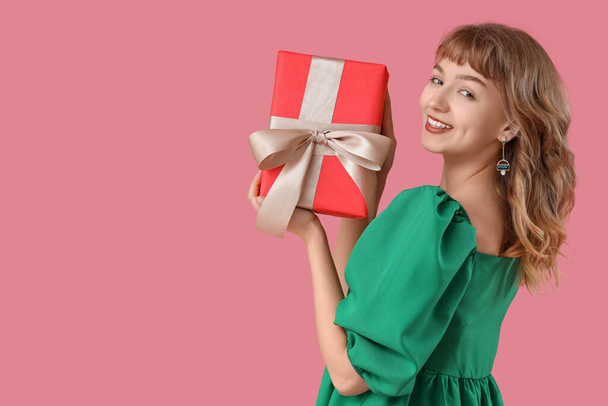 mooie jonge vrouw met gift box op roze achtergrond - Foto, afbeelding
