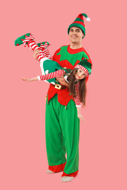 Vater mit seiner süßen kleinen Tochter im Elfenkostüm amüsiert sich auf rosa Hintergrund - Foto, Bild