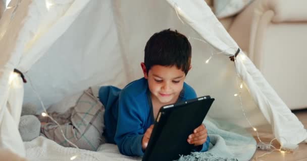 Tablet, χαλαρώστε και παιδί αγόρι σε μια σκηνή παίζοντας ένα online παιχνίδι στο διαδίκτυο στο σπίτι του. Ευτυχία, χαμόγελο και παιδί βλέποντας μια ταινία, βίντεο ή δείχνουν για την ψυχαγωγία στην ψηφιακή τεχνολογία στο φρούριο κουβέρτα - Πλάνα, βίντεο