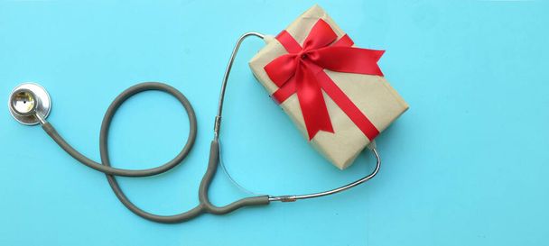 медицинский стетоскоп с подарочной коробкой на голубом пастельном фоне. Концепция Рождества и Новый год .horizontal фото - Фото, изображение