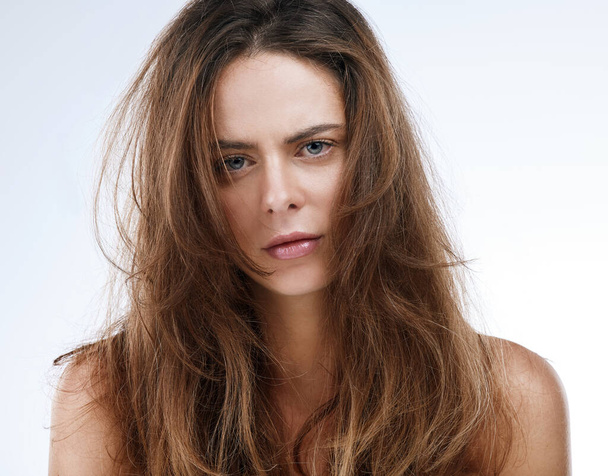 Portrait, messy hair and frustration with an unhappy woman in studio on a white background for beauty. Damaged, split ends or frizz and a young person looking upset with her haircare treatment. - Photo, Image
