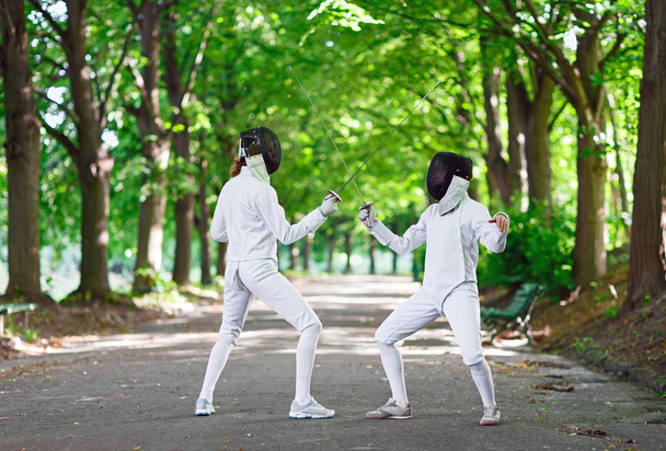Two rapier fencers women staying in park alley getting ready for - 写真・画像