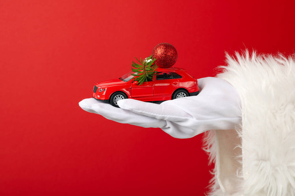 Ένα αυτοκίνητο με την διακόσμηση της Πρωτοχρονιάς, στο χέρι, στα χέρια του Αϊ Βασίλη. - Φωτογραφία, εικόνα