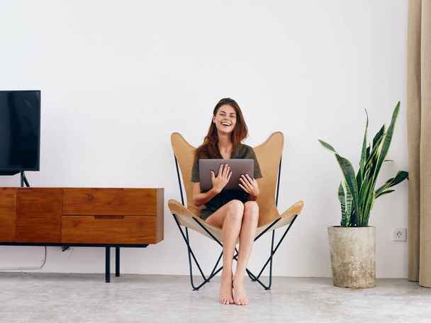 Nő diák tanulmány ül egy széken egy laptop munka otthon mosoly, modern elegáns belső skandináv életmód, másolás helyet. Kiváló minőségű fénykép - Fotó, kép