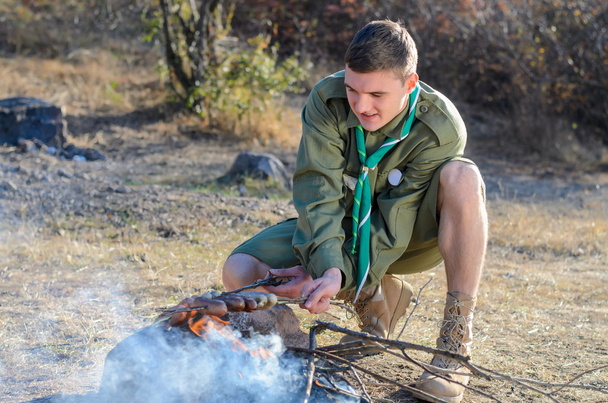 Boy Scout Cooking Sausages on Sticks over Campfire - Photo, Image
