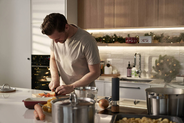 Valkoihoinen mies leikkaa vihanneksia ruokaa ennen joulua ruoanlaitto - Valokuva, kuva
