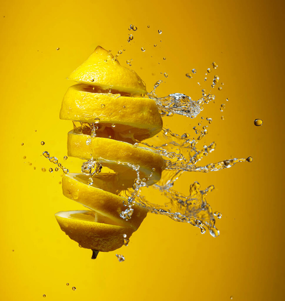 Limón fresco y salpicaduras de agua sobre un fondo amarillo. - Foto, Imagen
