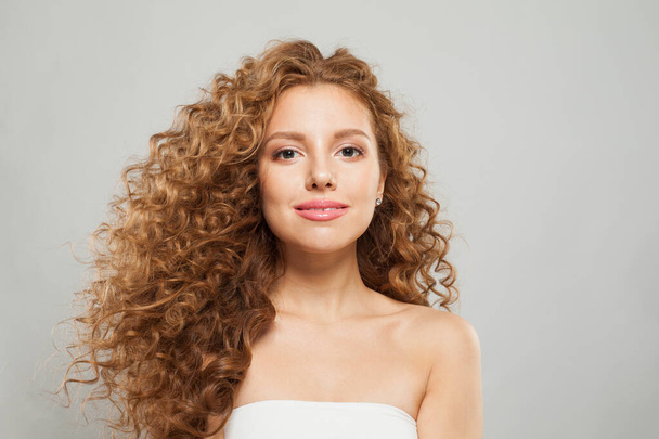 Stijlvolle jonge mode model vrouw met natuurlijke make-up, heldere huid en krullend kapsel poseren op witte achtergrond - Foto, afbeelding