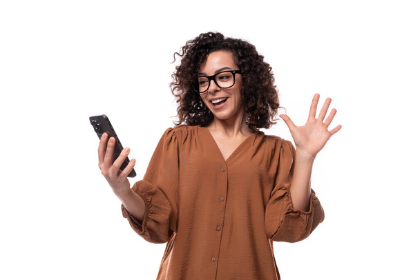 young successful pretty caucasian woman with curly black hair is using the phone. - Photo, Image