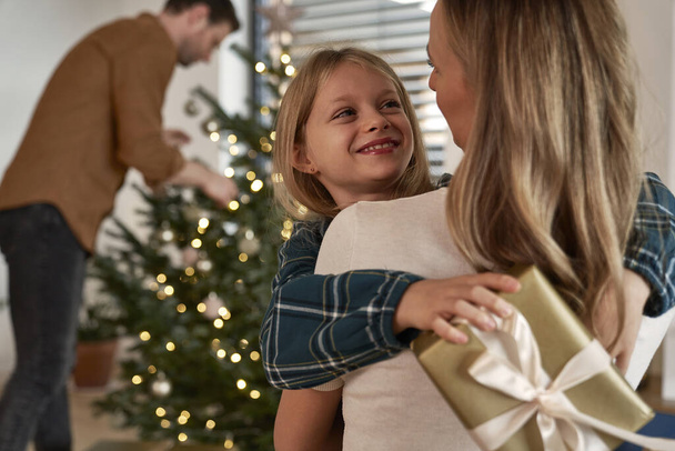 Family exchanging Christmas presents next to Christmas tree - Photo, Image