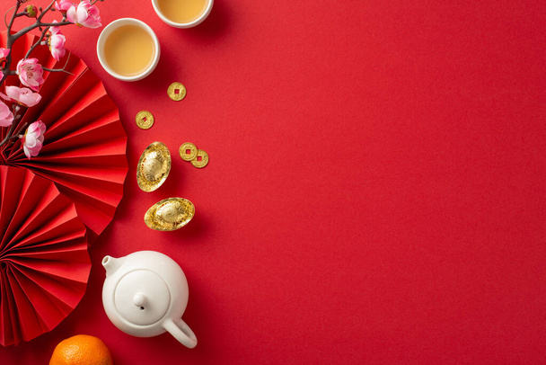 Celebra el Año Nuevo Chino con gran estilo. Vista superior de vibrantes fans rojos, set de ceremonia del té, espléndida fiesta, símbolos icónicos como monedas de la suerte. Abrace la prosperidad y la buena fortuna con familiares y amigos - Foto, imagen