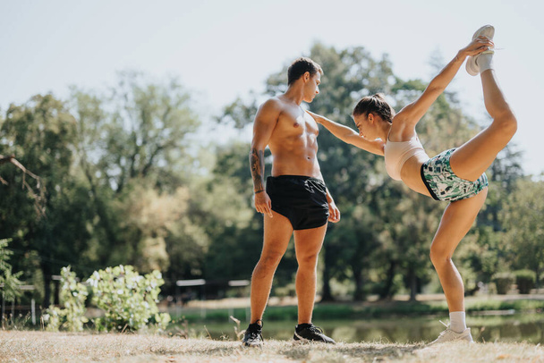 Young friends challenge each other in a park, practicing for an active day outdoors. They warm up, stretch, and work out their fit bodies. Positive results of professional athletes in sportswear. - Fotoğraf, Görsel