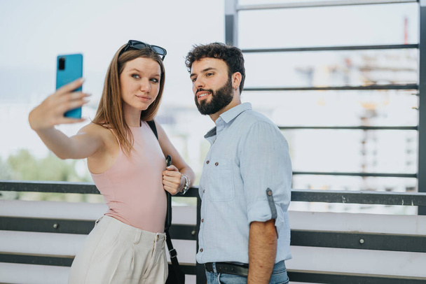 Młoda para robi sobie selfie, tworząc dobre wspomnienia podczas zdalnej pracy w miejskim centrum miasta. - Zdjęcie, obraz
