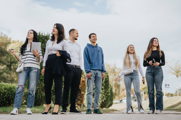 Группа студентов вузов, занимающихся в парке на открытом воздухе, обсуждающих темы, решающих задачи и готовящихся к экзаменам - Фото, изображение